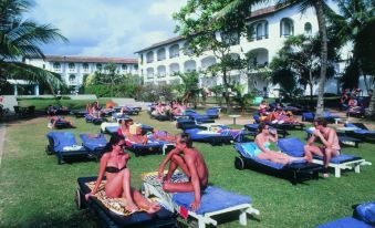 a large group of people is relaxing on lawn chairs in a grassy area near a building at Neptune