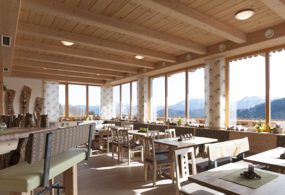 a large , open room with wooden tables and chairs arranged in a restaurant setting , overlooking a beautiful view at Hohenstein