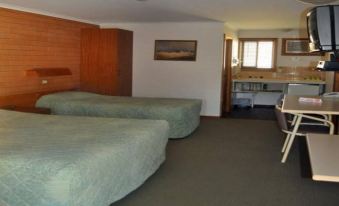 a hotel room with two beds , a desk , and a window , giving it a cozy and inviting atmosphere at Keith Motor Inn