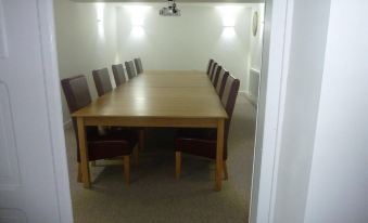 a long wooden table with brown chairs is set up in a room with white walls and a light fixture at Parrett Hotel