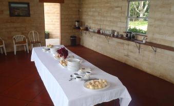 a long table with a white cloth and various food items is set up in a room at Alstonville Country Cottages