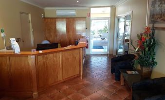 a modern office reception area with wooden paneling , tiled floor , and large windows leading to a swimming pool at Emerald Explorers Inn