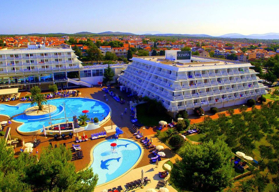 aerial view of a large hotel with a swimming pool surrounded by chairs and umbrellas at Hotel Olympia