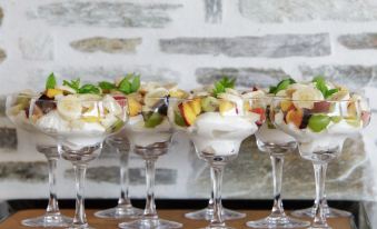 a row of small glasses filled with fruit and whipped cream are displayed on a table at Olga