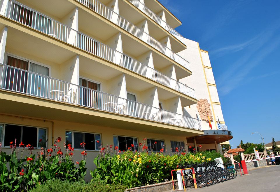 a white building with many balconies and flower arrangements is shown in front of a street at Linda