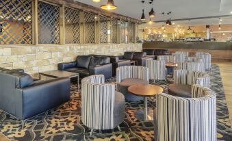 a modern lounge area with various seating options , including couches , chairs , and a dining table at Mercure Warragul