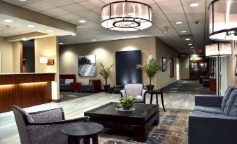 a hotel lobby with a large chandelier hanging from the ceiling , several potted plants , and a coffee table at Holiday Inn Weirton - Steubenville Area