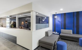 a modern hotel lobby with a reception desk , couches , and a man standing behind the counter at IStay Precinct Adelaide