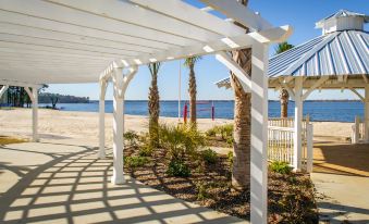 a white pergola with a beach view , surrounded by palm trees and a body of water at Holiday Inn Club Vacations Villages Resort Lake Palestine