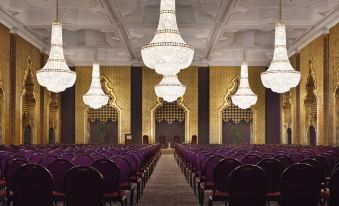 a large , empty conference room with rows of purple chairs and chandeliers hanging from the ceiling at Marriott Mena House, Cairo