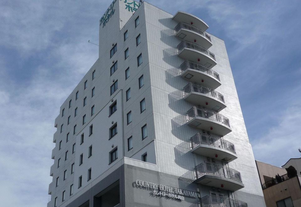 a tall white building with many balconies on the side , located in a city setting at Country Hotel Takayama