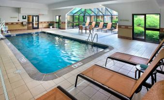 an indoor swimming pool surrounded by lounge chairs , where people are relaxing and enjoying their time at Courtyard Lincroft Red Bank