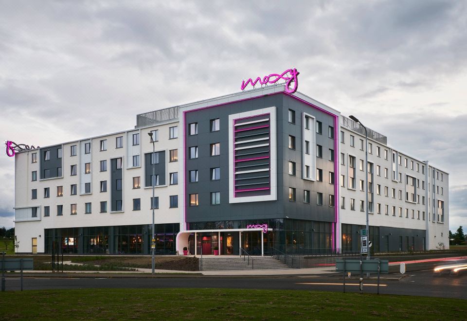 a modern building with a pink and black exterior , possibly a hotel or office building at Moxy Edinburgh Airport