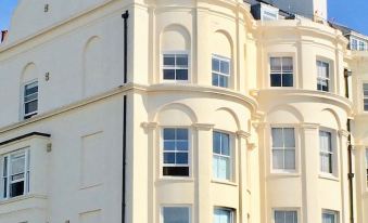 a white building with arched windows and a balcony on the second floor , situated in a sunny location under a clear blue sky at A Room with A View