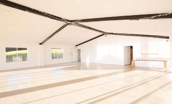 an empty , white room with a wooden floor and a large skylight above it , possibly for use as an exercise area at Ardeena