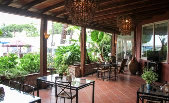 a cozy outdoor patio with wooden furniture , plants , and chandeliers , surrounded by lush greenery and trees at Park Hotel