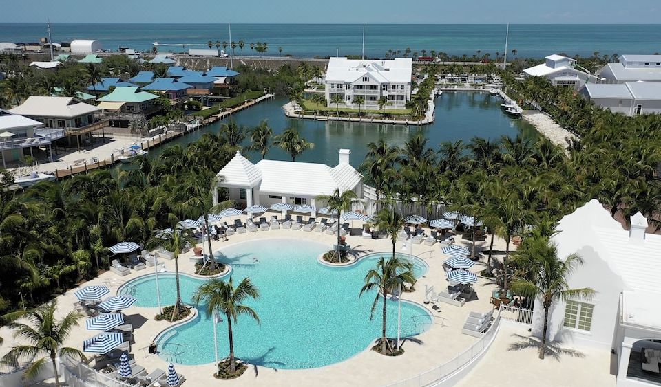 a large resort with a swimming pool surrounded by palm trees and a body of water at Isla Bella Beach Resort & Spa - Florida Keys