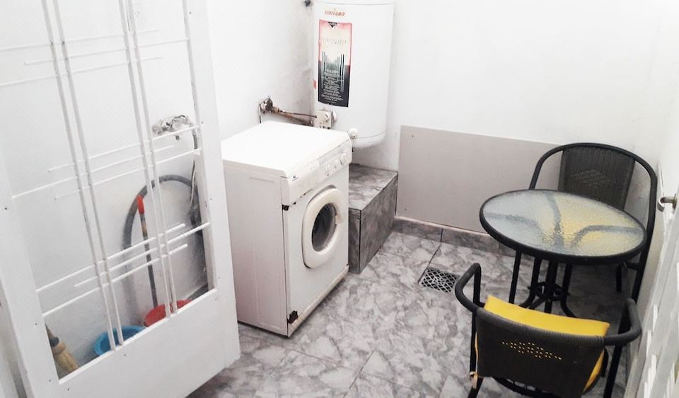 a white washing machine in a bathroom with a table and chairs , along with a water heater at Casa Mendoza