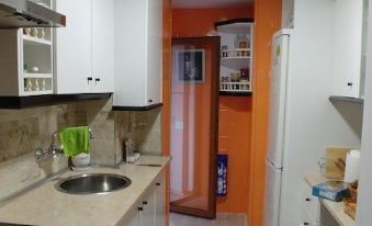 a kitchen with white cabinets and a black sink , next to an orange door leading to another room at Casa Sierra