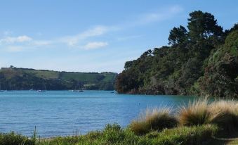 a serene landscape of a lake surrounded by green trees and hills under a blue sky at Vineyard Views