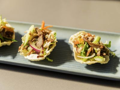 two plates of food , one with a salad and the other with a piece of meat on top , are presented on a blue tray at Ibis Melbourne Hotel and Apartments