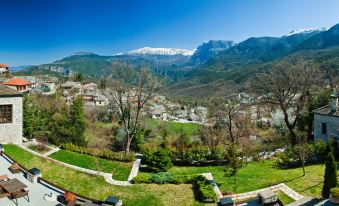 a panoramic view of a town nestled in the mountains with snow - capped peaks in the background at Aristi Mountain Resort