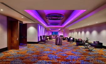 a large , well - lit room with purple and blue lights , carpeted floor , and multiple tables set up for a conference or meeting at Hyatt Regency Calgary