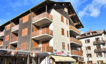 a large wooden building with balconies and a storefront , located in a city setting under a blue sky at San Anton