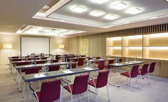 a large conference room with rows of chairs arranged in a semicircle , and a projector on the wall at Barceló Oviedo Cervantes