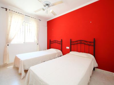 a bedroom with two beds , a window , and a red wall , under a white ceiling fan at Joli Joli Photo