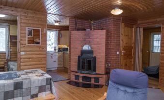 a cozy living room with wooden walls , a fireplace , and a blue couch near the window at Kuikka
