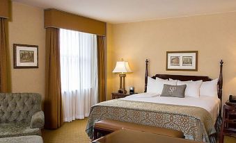 a large bed with a wooden headboard and white linens is in a hotel room with a window at The Saint Paul Hotel