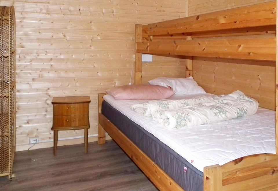 a bed with a wooden headboard and footboard is in a room with a wooden floor at Helgeland