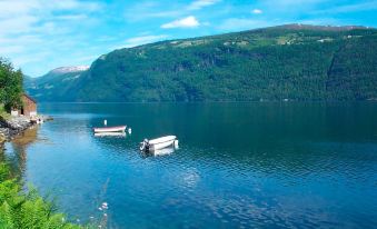 a serene lake with boats floating on the water , surrounded by green mountains and blue skies at Juv