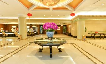 A spacious room is adorned with red flowers on the table and a chandelier in the front or another area at Shanghai Baoan Hotel