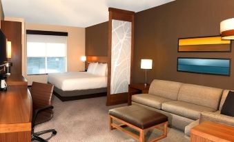 a modern hotel room with a bed , couch , and other furniture , as well as a dining table and chairs at Hyatt Place Augusta