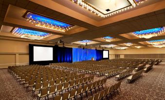 a large , well - lit conference room with rows of chairs arranged in front of a stage at Sheraton Grand Seattle