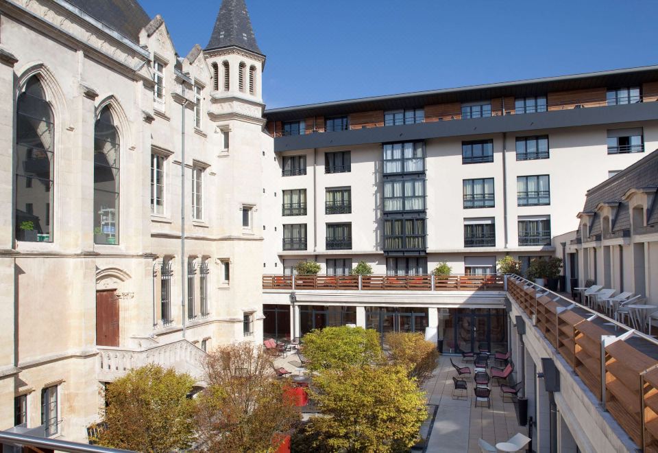 a modern building with a traditional architectural style , surrounded by lush greenery and outdoor seating areas at Best Western Premier Hotel de la Paix