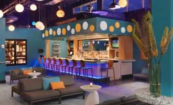 a brightly lit bar with various seating options , including couches and chairs , as well as a dining table at The Moonrise Hotel