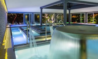 an indoor swimming pool surrounded by glass walls , with a waterfall feature in the middle of the pool at Chateau Royal Beach Resort & Spa, Noumea