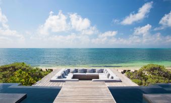 a wooden deck overlooking the ocean , with several chairs and a table placed on it at Nizuc Resort & Spa