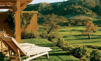 a beautiful outdoor setting with a wooden gazebo surrounded by lush green grass and trees , as well as a reclining chair placed on the grass at CordeValle