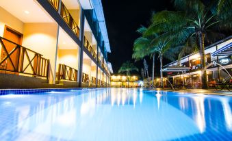 a nighttime view of a large outdoor swimming pool surrounded by buildings , with palm trees in the background at Summer Bay Resort, Lang Tengah Island