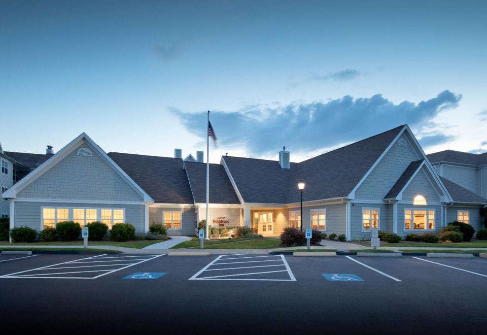 a large building with a parking lot in front of it , illuminated by the evening light at Residence Inn New Bedford Dartmouth