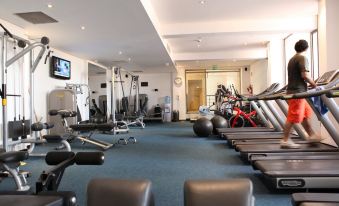 a well - equipped gym with various exercise equipment , including treadmills and stationary bikes , as well as chairs and tvs at Radisson Blu Hotel, Bamako