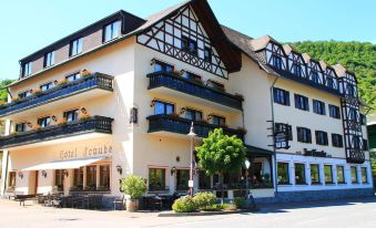 a large hotel building situated on a city street , with several cars parked in front of it at Moselhotel & Restaurant Zur Traube Gmbh