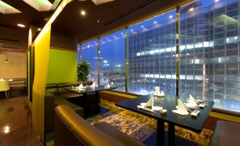 a dining room with tables and chairs set up for a meal , overlooking a cityscape at Airline Hotel