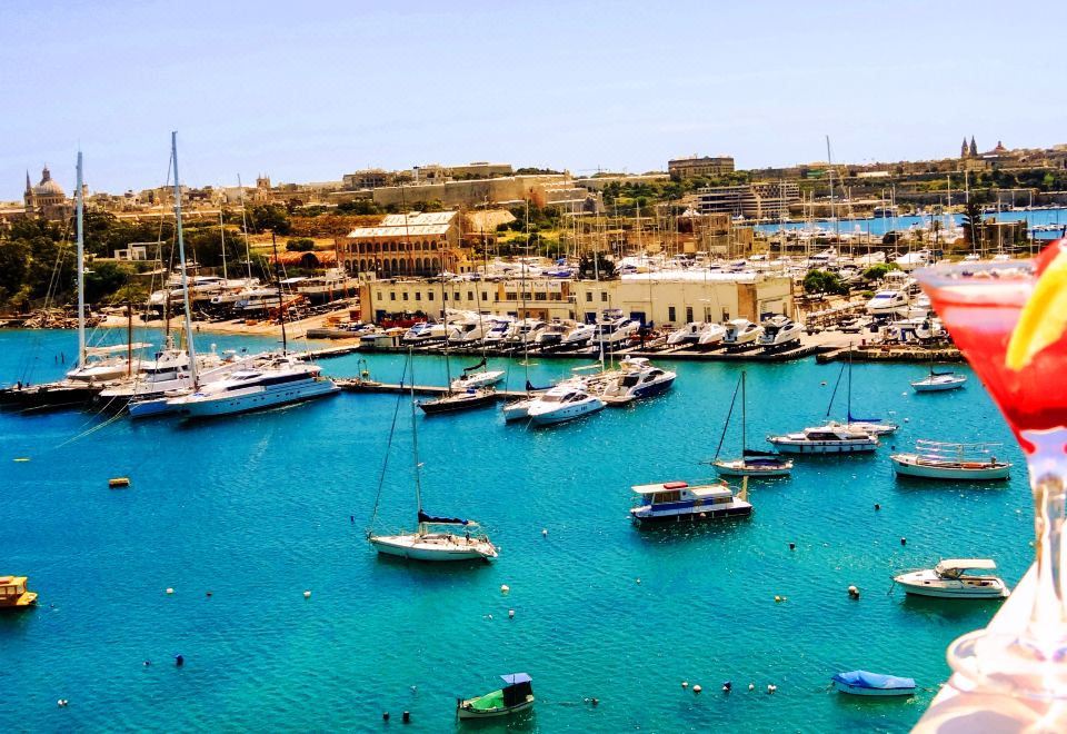 a panoramic view of a marina with numerous boats and yachts , surrounded by buildings and clear blue water at Hotel Kennedy Nova