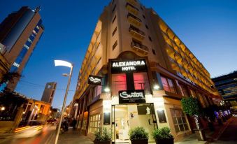 the alexandra hotel is a modern building with large windows and a red neon sign at Alexandra Hotel