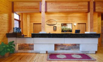a spacious reception area with wooden walls , a large flat - screen tv mounted on the wall , and a counter for customers to check in at Norfolk Lodge & Suites, Ascend Hotel Collection